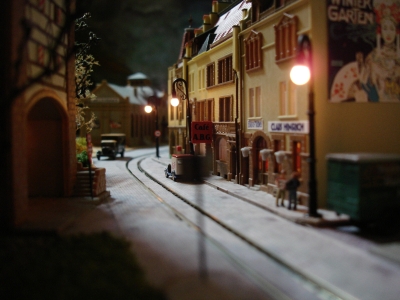 Een deel van de stad (in aanbouw, op de achtergrond is het stationsgebouw zichtbaar) waar een trammetje rijdt (simpel automatisch pendelbaantje).